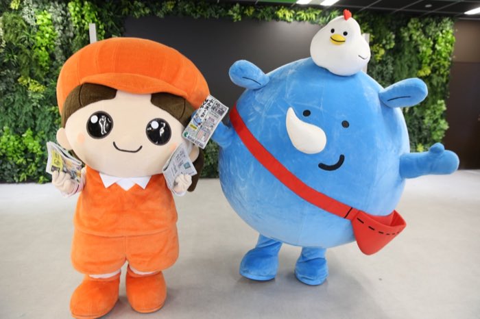 新聞を配るエミちゃんと地域のマスコットキャラクター